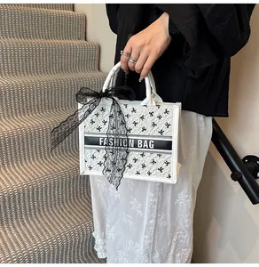 Detail of white tote bag with black bow print and lace silk scarf on the handle