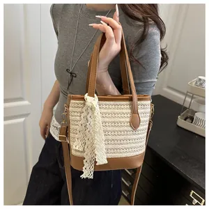 Detail of woven straw bucket bag featuring brown leather trim and white lace ribbon decor