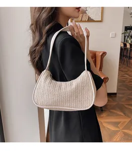 Fashionable woven beach shoulder bag with white leather strap shown on a female model
