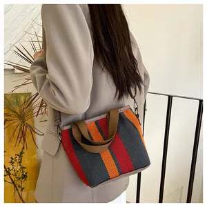Détail du sac cabas en toile rayée montrant les crochets en métal et la bandoulière grise
