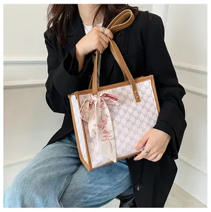 Detail view of large tote bag with NK pattern, brown handles and pink silk scarf