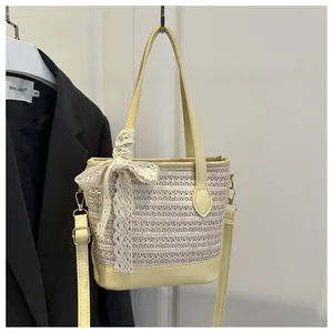 Detail view of woven straw tote bag with white lace bow and yellow leather handles