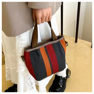 Détail du sac cabas à rayures multicolores avec poignées et anneaux métalliques