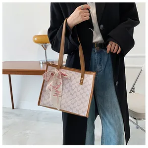 Chic beige monogram tote bag with brown leather handles and a red printed silk scarf detail