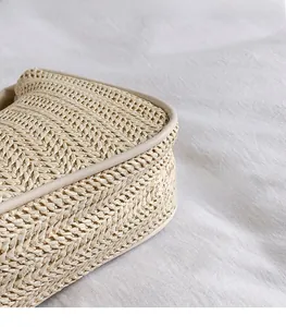 Detail of V-shape woven texture and cream leather edging on a summer shoulder bag