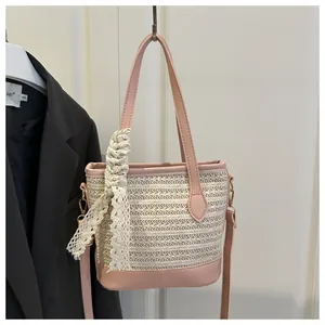 Detail of pink and beige woven straw bucket bag with lace charm and leather handles
