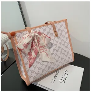 Detail of trendy tote bag featuring NK monogram print and elegant pink ribbon bow decoration