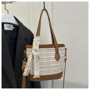 Detail of woven straw bucket bag with brown leather trim and white lace scarf decor