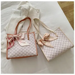 Detail view of large tote bags with NK monogram pattern and decorative silk scarves