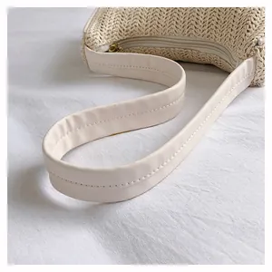 Detail of woven straw shoulder bag with creamy leather strap and gold zipper closure
