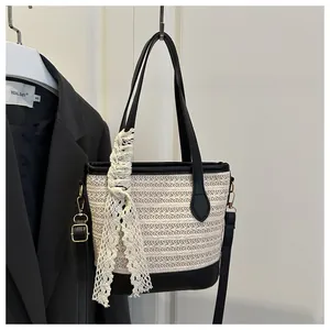 Detail of woven straw bucket bag with black leather trim and elegant white lace ribbon