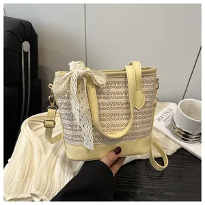 Detail of straw woven bucket bag with elegant white lace bow and yellow leather accents