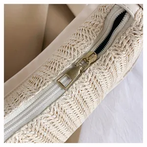 Detail of the vintage bronze zipper on a beige hand-woven straw shoulder bag