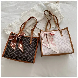 Detail showing two monogram tote bags with silk scarves and leather handles