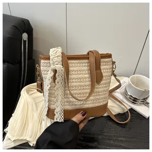 Detail of woven straw bucket bag with brown leather trim and white lace ribbon decoration