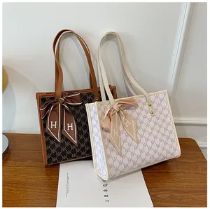 Close-up of brown and beige patterned tote bags with decorative bow scarves on a desk