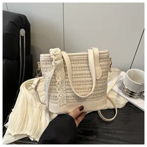 Detail of cream woven bucket bag with elegant lace bow and leather handles on white fabric