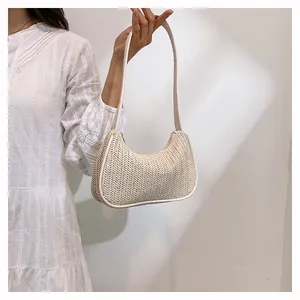 Close-up of beige woven crescent underarm bag with white leather trim and strap detail