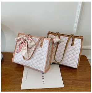 Detailed close-up of large monogram tote bags with decorative ribbon scarves and AK pattern