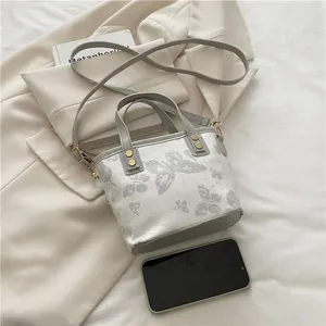Floral butterfly bucket bag in grey and ivory with dual handles and gold hardware details