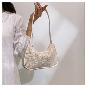 Detail of woven straw underarm bag with cream leather trim shown on a white dress model