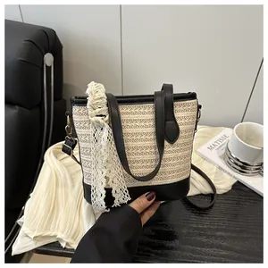 Close-up of beige woven bucket bag with black PU leather straps and white lace detail