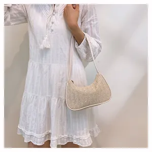 Detail of cream woven crescent bag with fine herringbone texture and slim shoulder strap