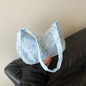 Detail of light blue hobo bag featuring bamboo leaf prints and smooth fabric texture