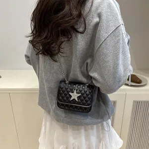 Sac bandoulière matelassé noir avec étoile argentée et chaîne porté par un mannequin
