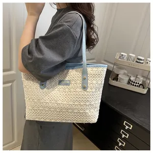 Detail of crochet tote bag with light blue leather straps and gold metal plaque