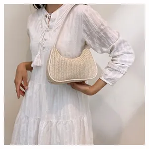 Close-up of beige woven straw baguette bag featuring herringbone texture and leather trim