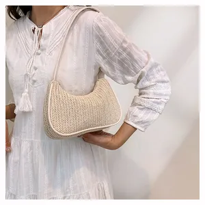 Detail of hand-woven beige straw texture and leather trim on a summer crescent shoulder bag