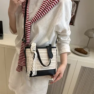 Straw bucket bag with black leather trim and lace bow worn with a white linen dress