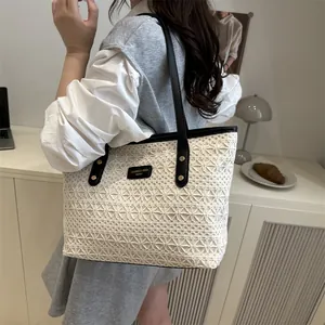 Large beige crochet tote bag with black shoulder straps and golden rivets detail