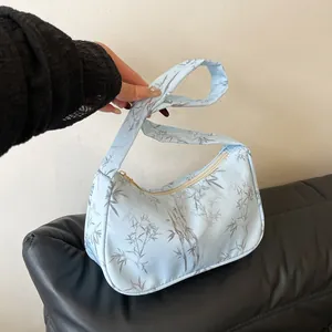 Detail of light blue hobo bag with satin texture and gray bamboo leaf pattern print