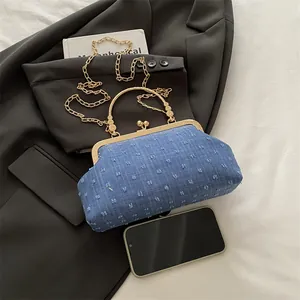 Sac à main bleu denim vintage avec fermoir doré et chaîne sur un blazer gris