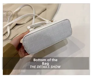 Flat bottom detail of a white crocodile texture shell bag with a matching shoulder strap