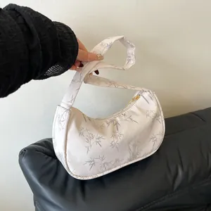 Detailed shot of white crescent bag with gray bamboo patterns and golden zipper detail