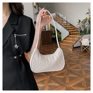 Detail of white woven underarm bag with herringbone texture and metal M pendant charm