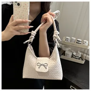 Detail of cream woven handbag with silver bow buckle and unique knotted strap design