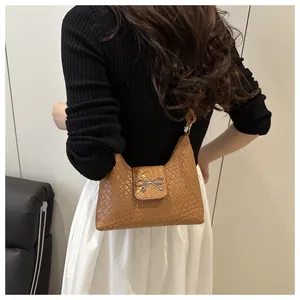 Brown woven texture handbag with silver bow metal clasp shown on female model shoulder