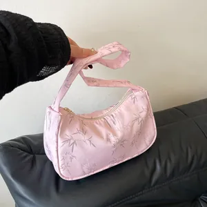 Detail of pink satin hobo bag with silver bamboo leaf print and gold zipper closure