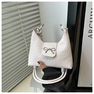Close-up of white woven texture handbag with silver bow detail and dual rope handles
