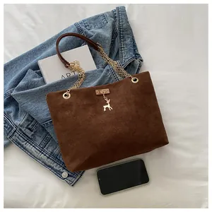 Detail of vintage brown suede tote bag with golden deer pendant and chain strap