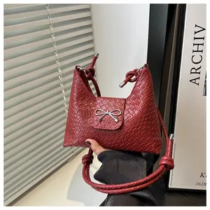 Detail of red woven PU handbag with silver metal bow and knotted rope shoulder strap