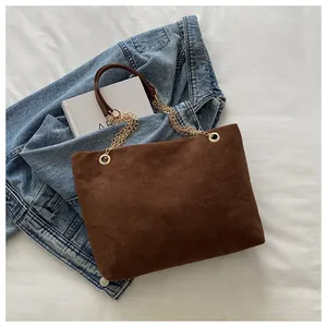 Detailed macro view of dark brown frosted suede tote bag with golden chain straps