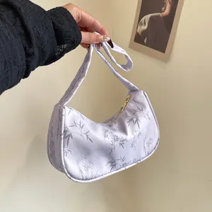 Detail of light purple satin underarm bag featuring grey bamboo leaf pattern and gold zipper