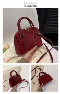 Detail view of wine red crocodile pattern shell bag with golden zipper and handles