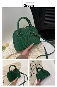 Close-up of green crocodile texture shell bag with gold hardware and zipper detail