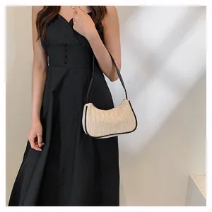 Woven straw shoulder bag with black leather trim shown on model for resort fashion